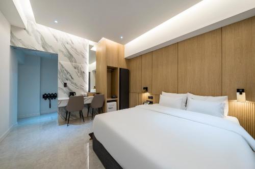 a bedroom with a large white bed and a desk at Brown Dot Hotel Pyeonghwa plaza in Mokpo