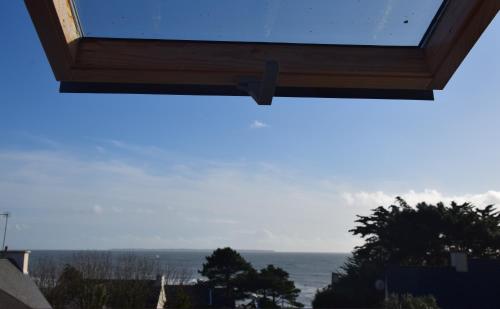 uma vista para o oceano a partir da janela de uma casa em La Maison du Pêcheur em Clohars-Carnoët