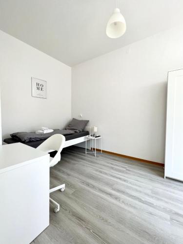 een witte kamer met een bed en een bureau bij Monteurzimmer in zentraler Lage in Emden