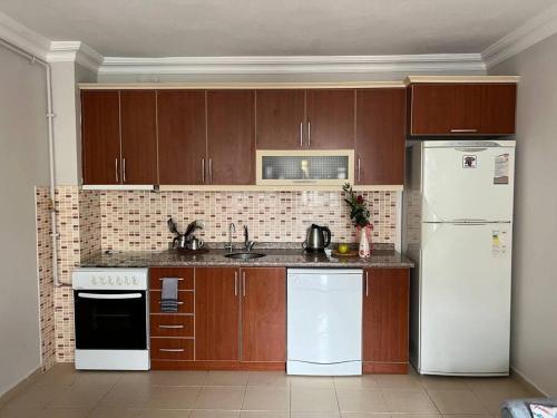 een keuken met houten kasten en witte apparaten bij Очень уютная квартира 2+1 in Antalya