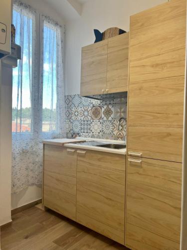una cocina con armarios de madera y una ventana en Grandchildren's house, en La Spezia