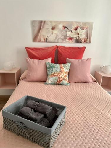 Una cama grande con almohadas rosas y una cesta. en Grandchildren's house, en La Spezia