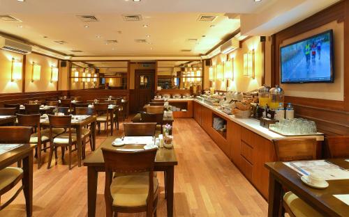 a restaurant with tables and chairs and a television at Taksim Pera Rose Hotel & Spa - Istiklal Street in Istanbul