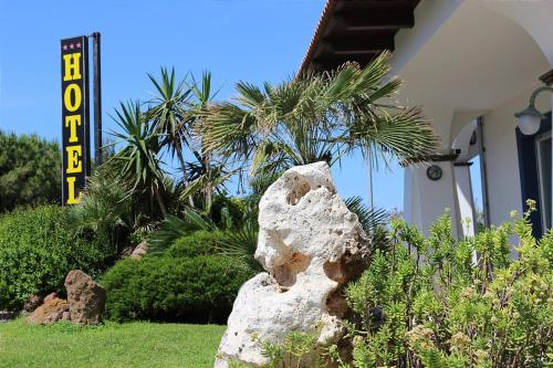 a rock sitting in the grass in front of a building at Hotel Rosa dei Venti in Castelsardo