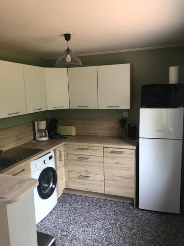 une cuisine avec des armoires blanches et un réfrigérateur blanc dans l'établissement Les grillons d’Eden, à Saint-Jean-de-Monts