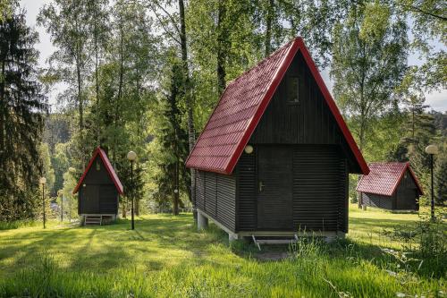 dwa małe domy na polu z drzewami w obiekcie Chatky Skalní mlýn Adršpach w Adršpach