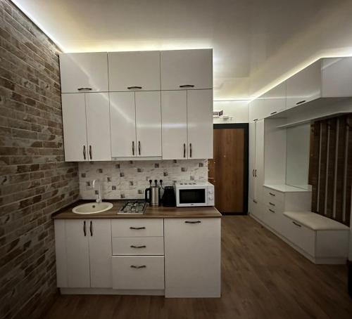 a kitchen with white cabinets and a sink and a microwave at Moonlight Apart-Hotel Batumi in Batumi
