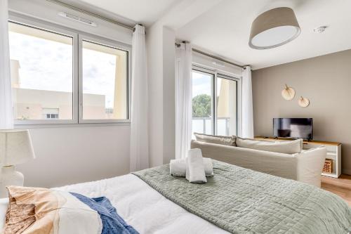 een slaapkamer met een bed, een bank en ramen bij OVELIA Montpellier - Les Balcons de Montcalm in Montpellier