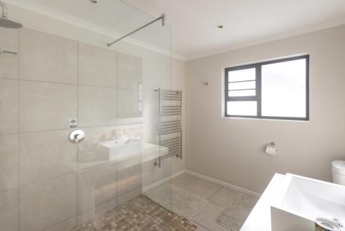 ein weißes Badezimmer mit Waschbecken und Dusche in der Unterkunft The Beauty of The Wildside 3 bedroom in Cape St Francis