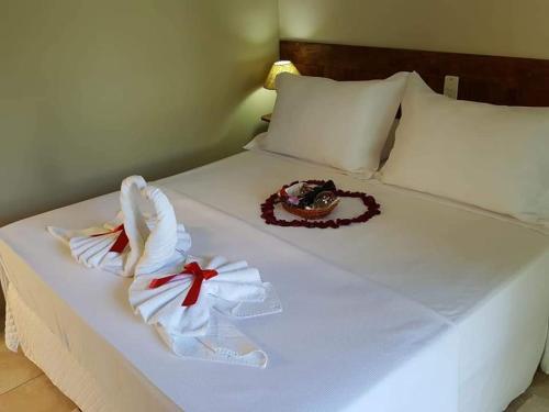 Una cama blanca con dos toallas y un sombrero. en Pousada Mirante Do Lago en Lindóia