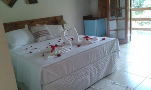 Un dormitorio con una cama blanca con rosas. en Pousada Mirante Do Lago en Lindóia