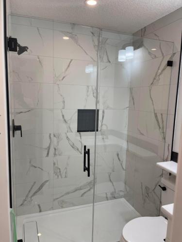 baño con ducha y puerta de cristal en Luxury One Bedroom Apartment, en Calgary