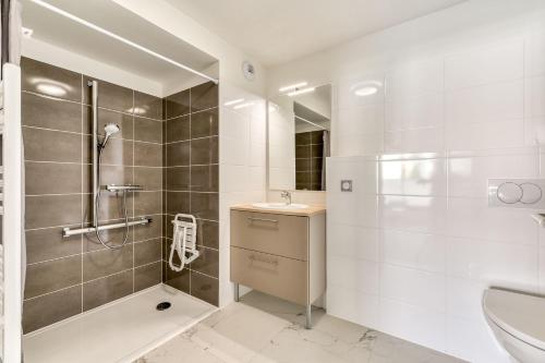 een badkamer met een douche, een wastafel en een toilet bij OVELIA Montpellier - Les Balcons de Montcalm in Montpellier