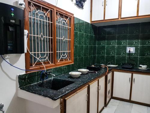 cocina con fregadero y pared de azulejos verdes en KORA'S HOME STAY en Tirupati