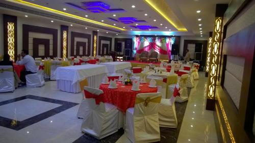 a large banquet hall with white tables and chairs at Hotel Seven Hills Tower in Agra