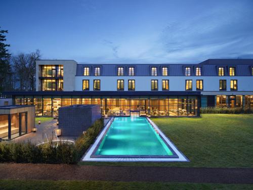 - un grand bâtiment avec une piscine en face dans l'établissement SCHLOSS Roxburghe, part of Destination by Hyatt, à Kelso