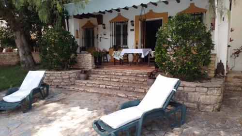 two chairs and a table in front of a house at Casa Rural El Olivar Ronda in Arriate
