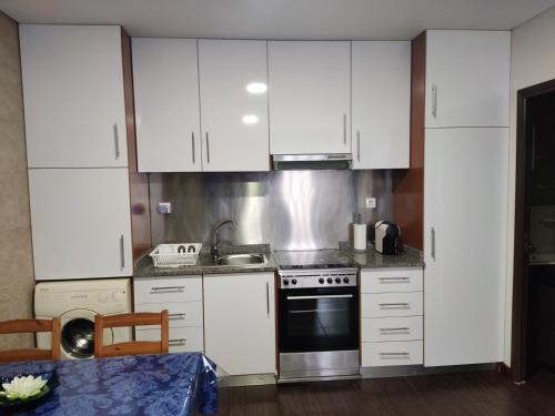 a kitchen with white cabinets and a stove top oven at Casa de férias e fins de semana, 5 in Esposende