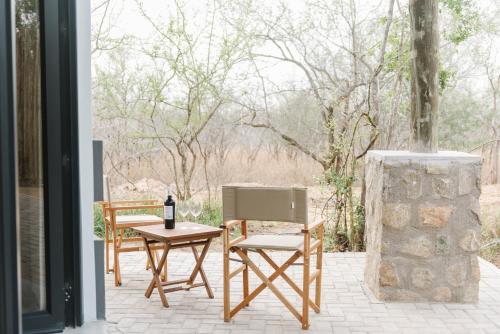 patio con 2 sedie e tavolo con una bottiglia di vino di The Orpen Kruger a Welverdiend