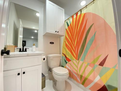 baño con aseo y cortina de ducha colorida en Tropical Springs Studio Apartment Two Queen Beds, en Galveston