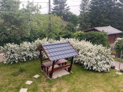 a wooden bench in a yard with white flowers at Lilakő Apartman in Mátraszentimre