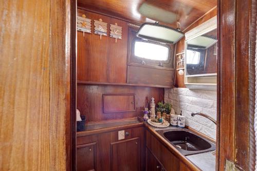 a kitchen with wooden cabinets and a sink and a window at Aloha Jak's Boat in Alassio