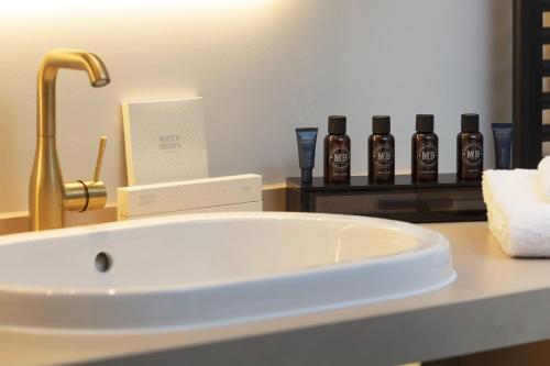 a bathroom counter with a sink and three bottles of alcohol at SCHLOSS Roxburghe, part of Destination by Hyatt in Kelso