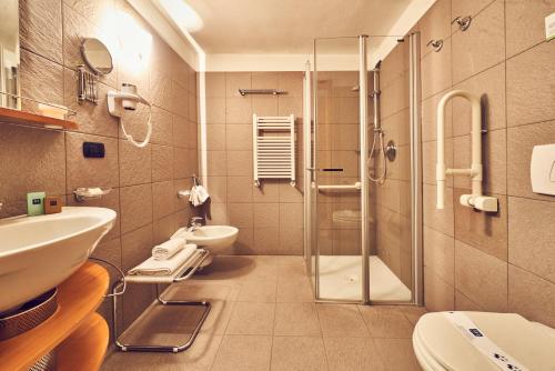 a bathroom with a shower and a sink and a toilet at iH Hotels Courmayeur Mont Blanc in Courmayeur