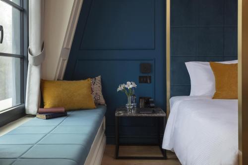 a blue bedroom with a bed and a side table at SCHLOSS Roxburghe, part of Destination by Hyatt in Kelso