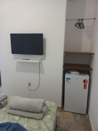 um quarto com uma televisão na parede e um frigorífico em Suíte e Apartamento Angra dos Reis em Angra dos Reis