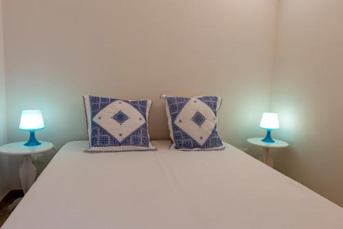 a bed with blue and white pillows and two lamps at Casa Conte Pio in Marettimo