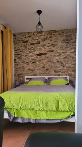 een slaapkamer met een groen bed en een bakstenen muur bij Au cœur de Pornic in Pornic