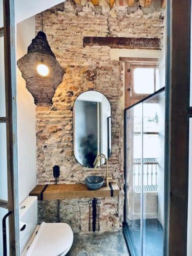 a bathroom with a stone wall with a sink and a mirror at Casa Doggio, Loft con historia in Cartagena