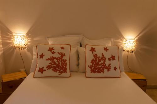 a bed with two pillows on it with two lights at Casa Conte Pio in Marettimo