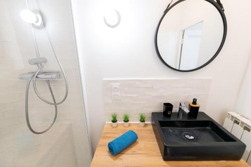 La salle de bains est pourvue d'un lavabo noir et d'un miroir. dans l'établissement KASA BOHEME - Centre ville - Spacieux et tout équipé, à Saint-Étienne