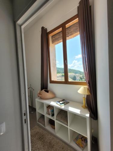 Cette chambre dispose d'une fenêtre et d'une étagère avec des livres. dans l'établissement Charmant Duplex au cœur du village, à Cotignac