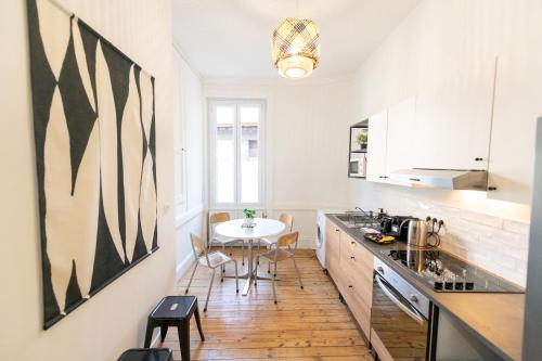 une cuisine avec une table et une salle à manger dans l'établissement La Bohème, appartement chaleureux et décoré avec goût, à Saint-Étienne