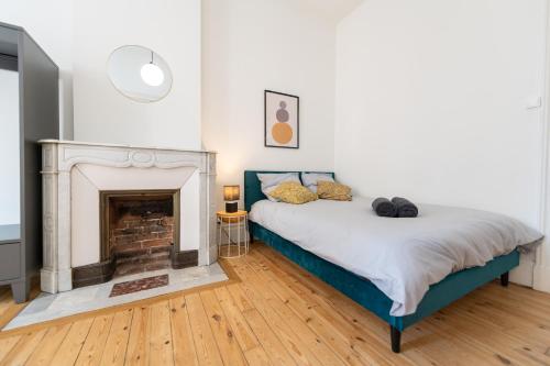 Un dormitorio con una cama y una chimenea. en La Bohème, appartement chaleureux et décoré avec goût, en Saint-Étienne