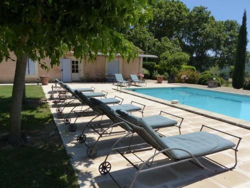 une rangée de chaises longues à côté d'une piscine dans l'établissement Luberon - Mas du Grand Saint Julien, à Rustrel