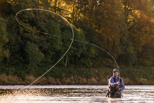 a man is in the water fishing with a rod at SCHLOSS Roxburghe, part of Destination by Hyatt in Kelso