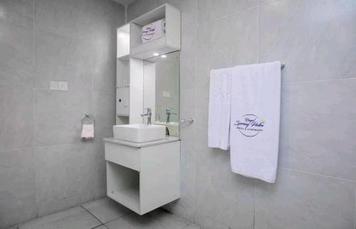 a white bathroom with a sink and a mirror at The Palms Hotel in Abuja