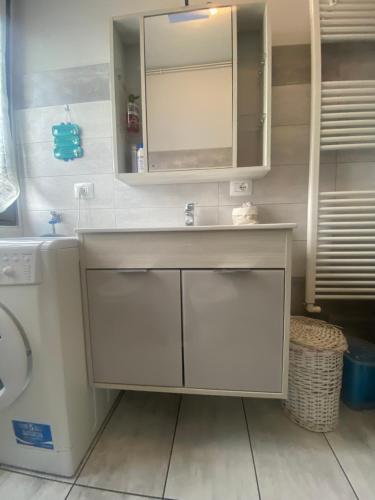 a white bathroom with a sink and a mirror at la maison du soleil in Colazza