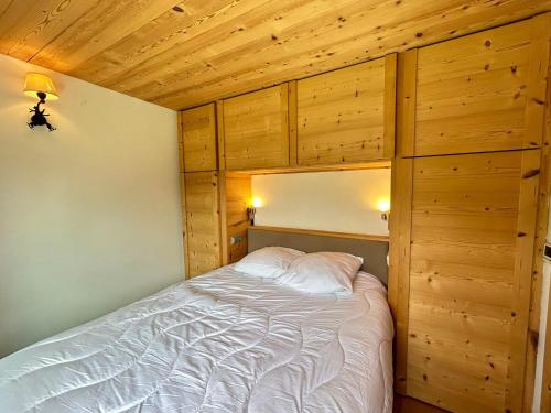 une chambre avec un lit dans une pièce aux murs en bois dans l'établissement Les Gets - Appartement Le Grizzli - Pistes des Chavannes et Piscine Chauffée - FR-1-623-43, aux Gets