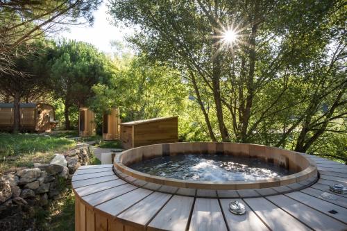a hot tub on a wooden deck in a garden at Village Huttopia Dieulefit in Dieulefit