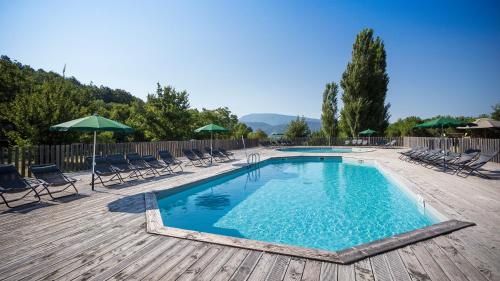 einen Pool mit Stühlen und Sonnenschirmen auf einer Holzterrasse in der Unterkunft Village Huttopia Dieulefit in Dieulefit