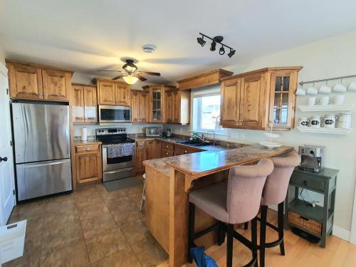 une cuisine avec des placards en bois et un îlot avec des tabourets de bar dans l'établissement Peaceful Water View House!, à Charlottetown