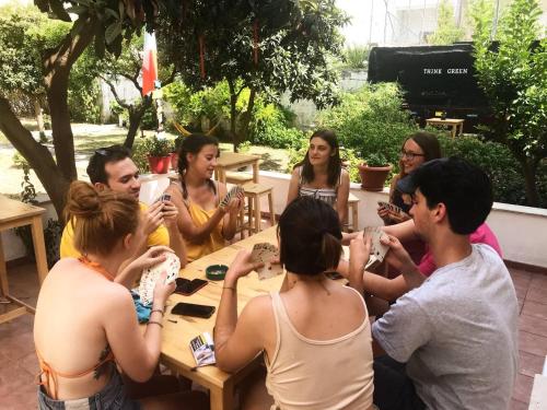 un grupo de personas sentadas alrededor de una mesa en Urban Oasis Hostel, en Lecce