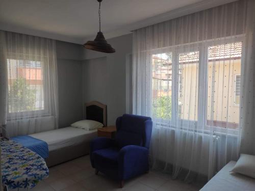 Schlafzimmer mit einem Bett, einem Stuhl und Fenstern in der Unterkunft Ege Homes in Ula