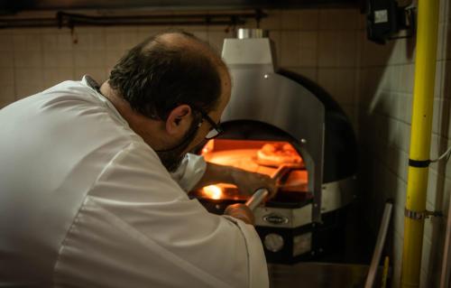 a man is putting a pizza into an oven at Polyrizos Hotel in Rodakino