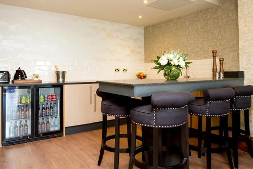 a kitchen with a bar with stools and a refrigerator at The Shankly Hotel in Liverpool